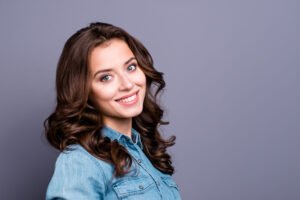 Profile side portrait of nice charming tender attractive cheerful magnificent adorable girl with wavy hair in casual denim shirt, isolated over grey background