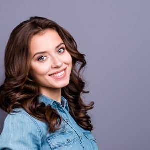 Profile side portrait of nice charming tender attractive cheerful magnificent adorable girl with wavy hair in casual denim shirt, isolated over grey background